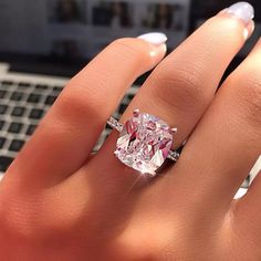 a woman's hand with a ring on it and a pink diamond in the middle