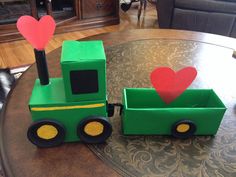 a green toy train sitting on top of a table next to a heart shaped tree