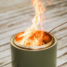 a small fire pit sitting on top of a wooden table next to a cup filled with water