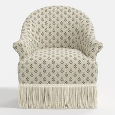 an upholstered chair with fringe trim