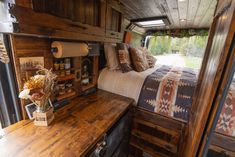 a bed sitting in the back of a truck next to a wooden desk and window