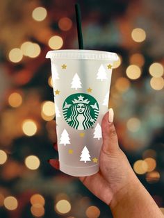 a hand holding a starbucks cup in front of a christmas tree