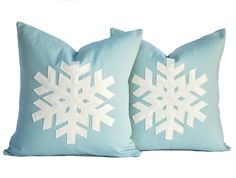 two blue pillows with white snowflakes on the front and back, one in light blue