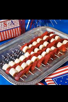 red, white and blue fruit skewers on a tray