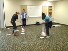 two women are standing in a room with whiteboards on the wall and one woman is holding a pole