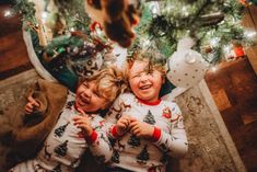 two children laying on the floor in front of a christmas tree