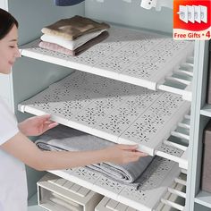 a woman is looking at some folded towels on shelving shelves in a store or office