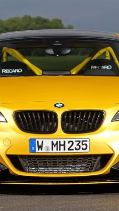 a yellow bmw z4 is parked on the road with its hood up and windows open