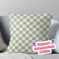 a green and white checkerboard pillow with the words support independent artists on it