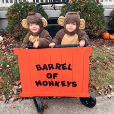 two young boys dressed in monkey costumes riding on a cart with the words barrel of monkeys written on it