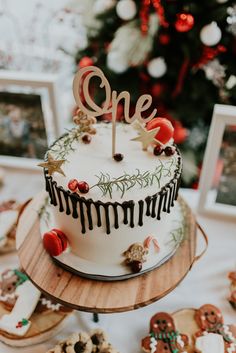 a decorated cake sitting on top of a wooden table next to cookies and other foods