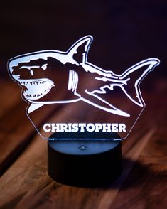 a light up shark on top of a wooden table with the words christopherer written in white