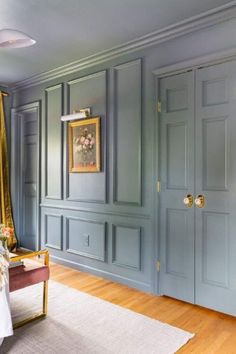 a bedroom with blue walls and gold trimmings on the door, bed in foreground