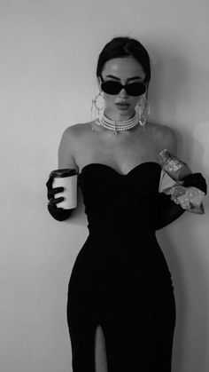 a woman in a black dress holding a coffee cup