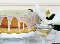 a cake with icing on it sitting next to a wine glass and some flowers