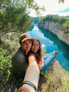 a man and woman taking a selfie on the edge of a cliff overlooking a river