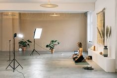 a woman is sitting on the floor in front of a camera and lighting equipment,