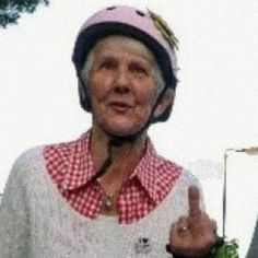 an older woman wearing a helmet giving the peace sign