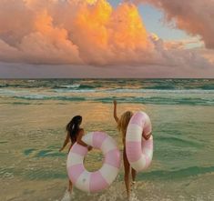 two women in the ocean with large pink and white life preservers