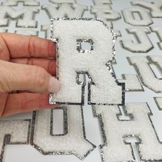 someone is making letters out of sequins with their fingers and thumbnails