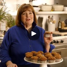 a woman standing in front of a cake and muffins on a white plate