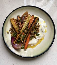 a white plate topped with carrots, lentils and yogurt