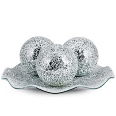 three silver balls sitting on top of a glass plate