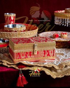 a red and gold box sitting on top of a table next to two silver dishes