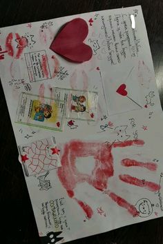 a child's handprint on a piece of paper with red ink and hearts