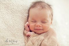 a baby sleeping on top of a blanket with his hands under his chin and eyes closed