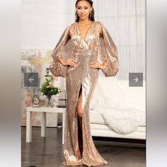 a woman standing in front of a couch wearing a gold dress