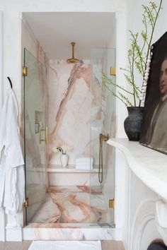 a bathroom with marble walls and flooring next to a painting on the shower wall