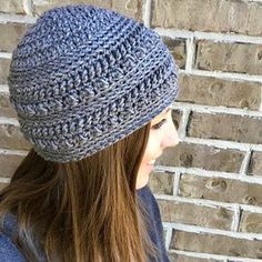 a woman wearing a knitted hat standing in front of a brick wall