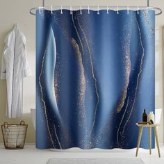 a shower curtain with blue and gold designs on the outside, hanging in a bathroom