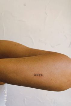 a woman's arm with the word xoxo tattooed on her left arm