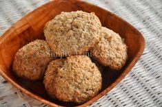 four oatmeal muffins in a wooden bowl on a white tablecloth