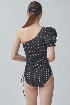 Retro-inspired one piece swimsuit featuring textured fabric, a slanted neckline with single shoulder design, a short puff sleeve with ruffle trim, detachable pad cups, ruched details at one side with a cinching tie, and the moderated fit bikini bottom in vintage dots.Size Guide:Size (in)USBustWaistHipS4-632-3424-2634-36M8-1034-3626-2836-38L12-1436-3828-3038-40 Fitted One-shoulder Swimwear With Ruffles, Fitted Swimwear With Asymmetrical Neckline For Summer, Short Puff Sleeve, Shoulder Design, Black Swimsuit, Textured Fabric, Retro Inspired, Ruffle Trim, One Piece Swimsuit