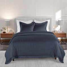 a bed with blue comforter and pillows in a room next to two nightstands