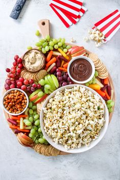 a platter filled with grapes, carrots, crackers, and other snacks