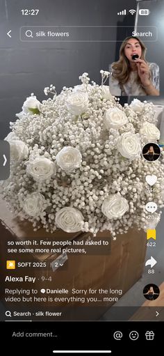 a bouquet of white flowers sitting on top of a wooden table next to a phone