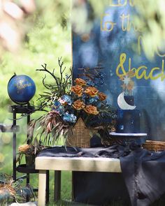 a table topped with flowers next to a blue and white sign that says do it to the moon