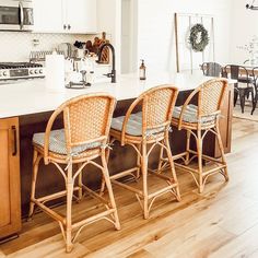 three wicker bar stools sitting on top of a kitchen island