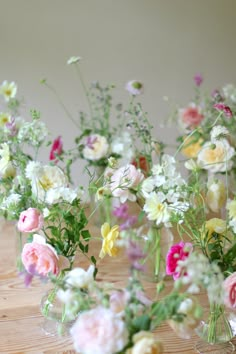 several vases filled with flowers on top of a wooden table