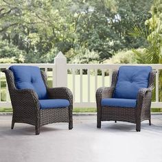 two wicker chairs with blue cushions on a patio