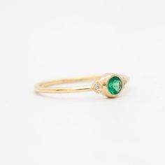 a gold ring with a green stone in the center and two diamonds on each side