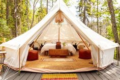 a large tent with two beds inside of it in the middle of some trees and grass