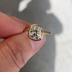 a person holding a ring with a diamond in it's middle and the other hand