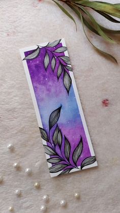 a purple and blue bookmark sitting on top of a white table next to pearls