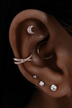 a woman's ear with three different types of piercings