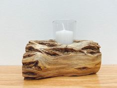 a candle holder made out of driftwood with a glass on the top and white wall in the background